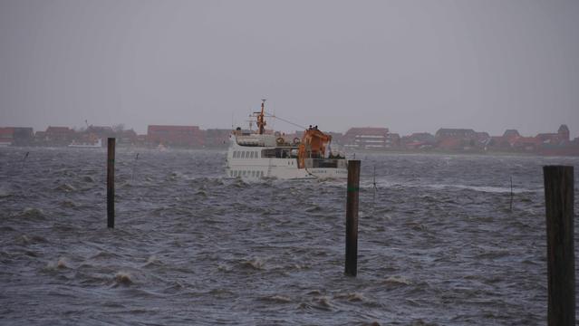 Weißes Schiff bei der Hafenausfahrt. Graubraunes Wasser Spritzt
