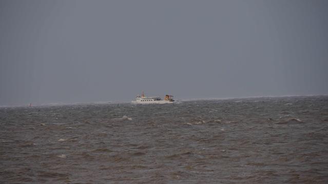 Weißes kleines Schiff auf grauem aufgewühlten Meer