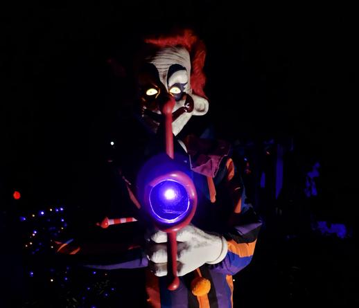 an automated clown shoots a purple laser light at the camera