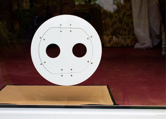 A white Petflap draughtproof pet door set into glass, viewed from outdoors