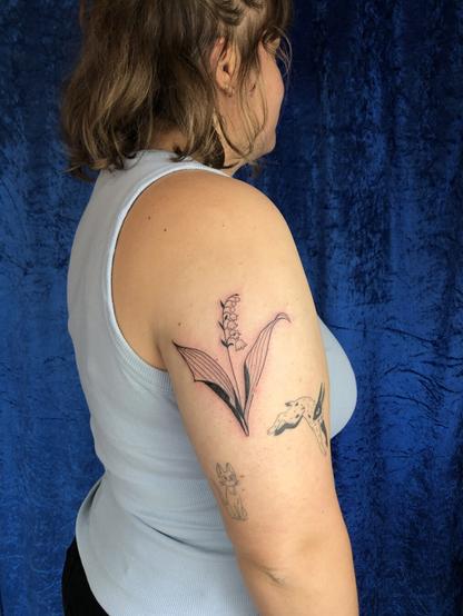 Photo du bras de Camille, sur lequel est tatoué un brin de muguet