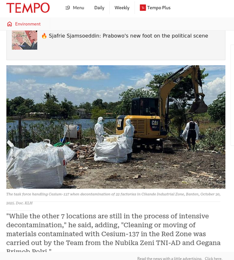 People in Hazmat suits cleaning up scrap metal and other items contaminated with Cesium-137 next to a river.