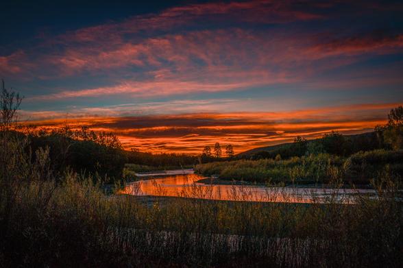 orange light from the sun about to rise hitting clouds at the horizon at the Chama River Canyon Wilderness in New Mexico