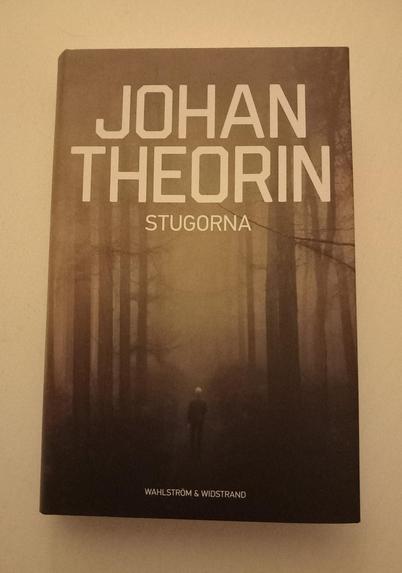Ett bokomslag, trädstammar I gulaktigt sken. Text: Johan Theorin Stugorna