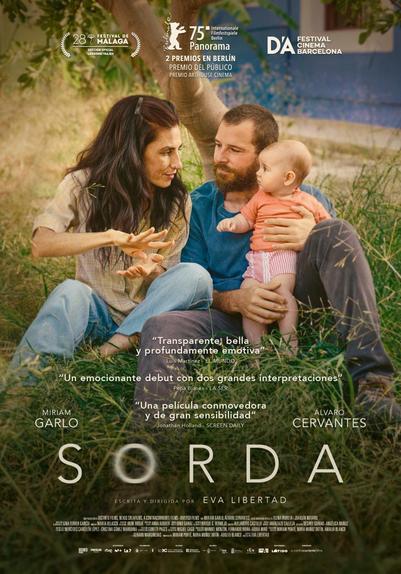 Spanisches Filmposter für den Film “Sorda”. Das junge Elternpaar sitzt mit ihrem Baby im Gras. Er ist an einen Baum angelehnt und hält das Baby. Beide schauen die Mutter an, die Blickkontakt mit ihrem Baby hält, während sie gebärdet.
