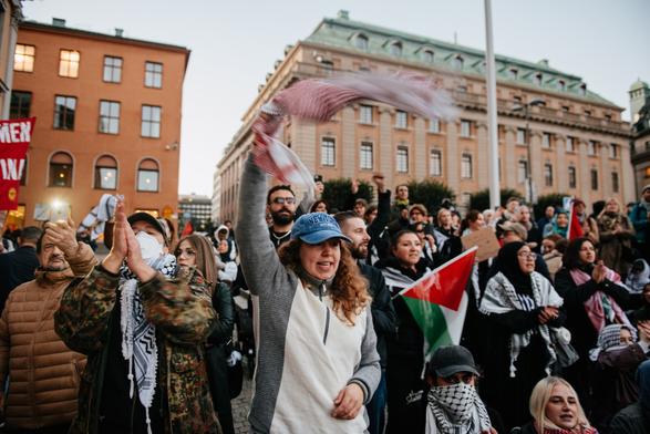 One lady (she is wearing a cap)  is circling around her keffiyeh above her head, and a lot of protesters are behind her.