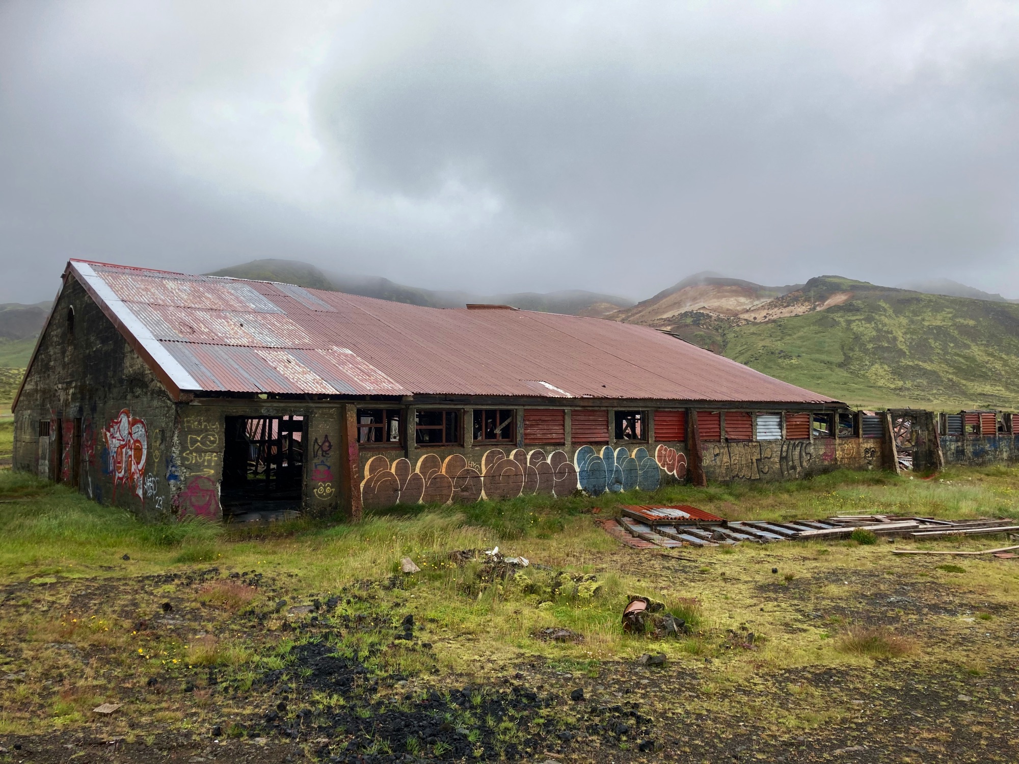 An abandoned old barn covered in graffiti on a cloudy day.