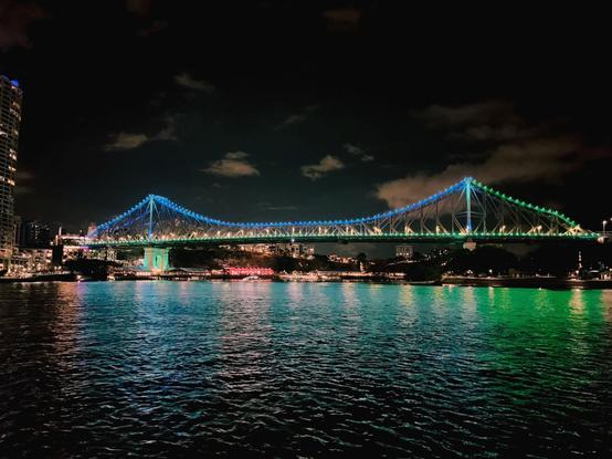 The Story Bridge reflects its blue green lights on the Brisbane River.