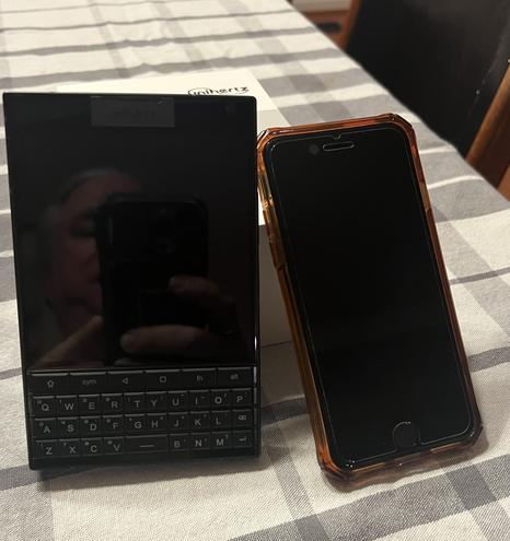 Photo of a titan 2 phone leaning against its box with an iPhone SE next to it.