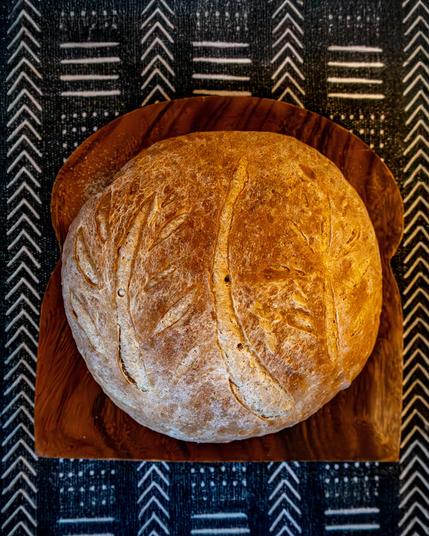 A boule of bread rests on a bread slice shaped plate