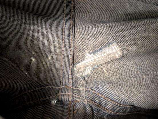 The same hole but viewed from inside the jeans, light shining through the hole.