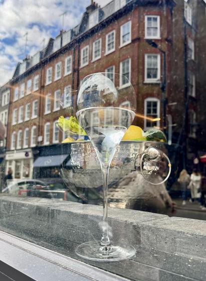 London street view of red brick building overlaid with floating reflection of curved crystal water glass and hammered ice bucket