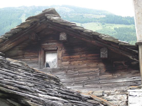 In einem Tal in Graubünden steht dieses Blockhaus, das mit Schieferschindeln gedeckt ist.
Es hat bereits viele Generationen überdauert. Ein Fenster im oberen Geschoss lässt einen gemütlichen Innenraum vermuten.