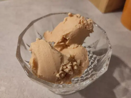 Drei unförmige Kugeln der Hagebutten-Birnen Eiscreme in einer gläsernen Dessertschale