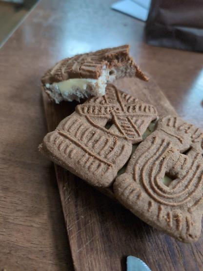 Een desemboterham met boter en drie speculaasjes erop liggend op een plankje