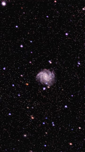 A spiral galaxy is depicted in the center, surrounded by numerous stars against a dark starry background. The galaxy displays swirling arms and a faint glow, illustrating celestial beauty.
Galaktyka spiralna jest przedstawiona w centrum, otoczona licznymi gwiazdami na ciemnym gwiaździstym tle. Galaktyka pokazuje wirujące ramiona i słabą poświatę, ilustrującą niebiańskie piękno.