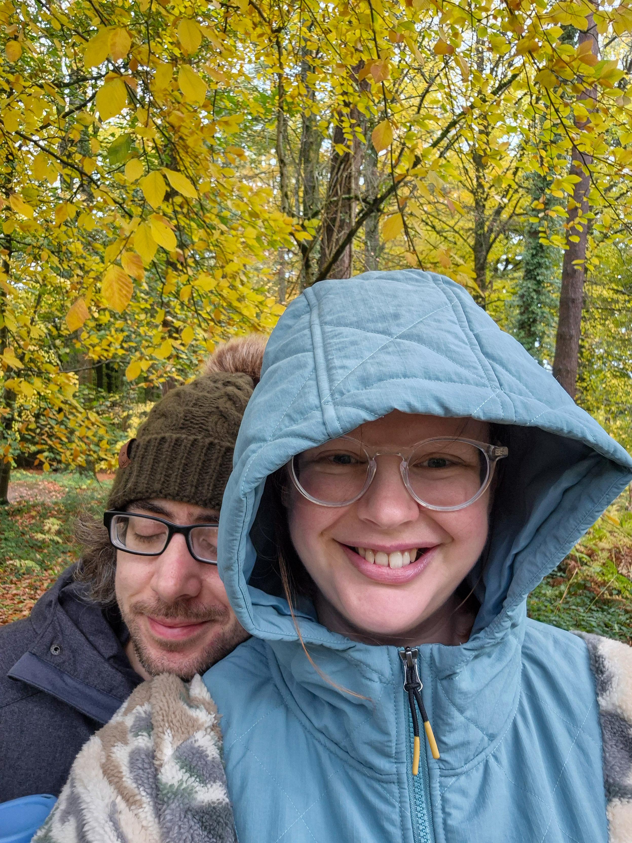 Rosie and Chris are in the woods, he looks like he has fallen asleep leaning on her nice new fleece, she is grinning