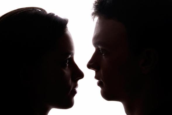 Una mujer y un hombre mirándose muy cerca con un fondo blanco. (Getty Images)