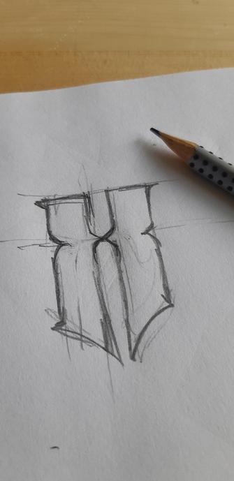 Photo d'un croquis dans un calepin à dessin. Un X stylisé, s'approchant d'une typo gothique.