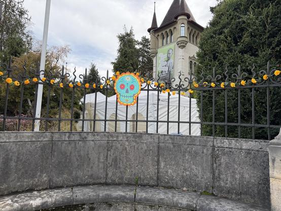 Links vom Eingang ein bunter Schädel, links und rechts farbige Blumen
To the left of the entrance is a colorful skull, with colorful flowers to the left and right