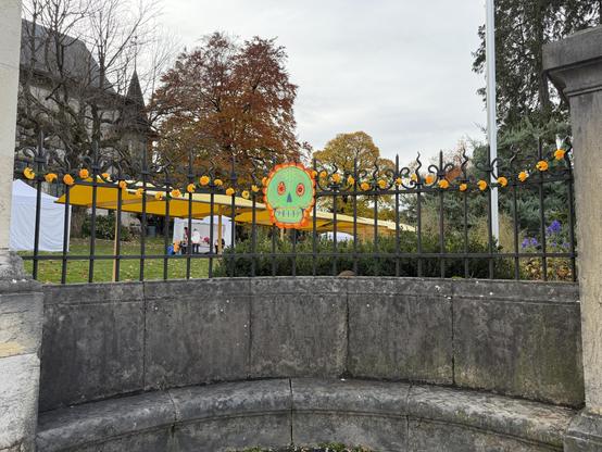 Rechts vom Eingang ein bunter Schädel, links und rechts farbige Blumen
To the right of the entrance is a colorful skull, with colorful flowers to the left and right