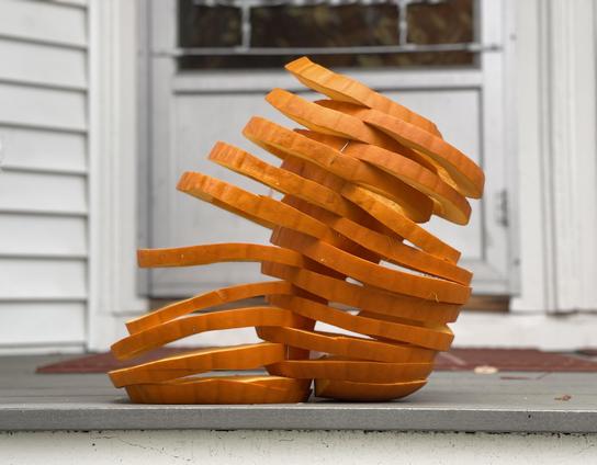 Two pumpkins, each cut into ten horizontal slices. The slices are stacked overlapping. They start overlapping a little bit at the bottom and gradually overlap more and more, so at the top they nearly merge. This gives the pumpkins the appearance of being smushed together. and the whole structure is tilted toward the right. An interesting artifact is that inside where they overlap takes on the shape of a cone or a tornado.