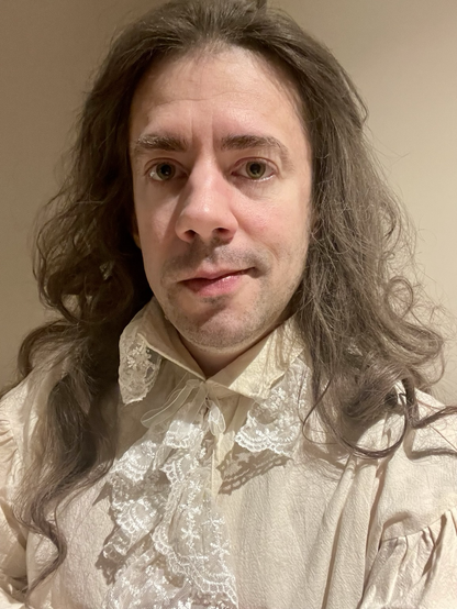 Ansiktsbild av en man med långt rufsigt, pudrat hår och en 1700-tals-skjorta med spetskrås