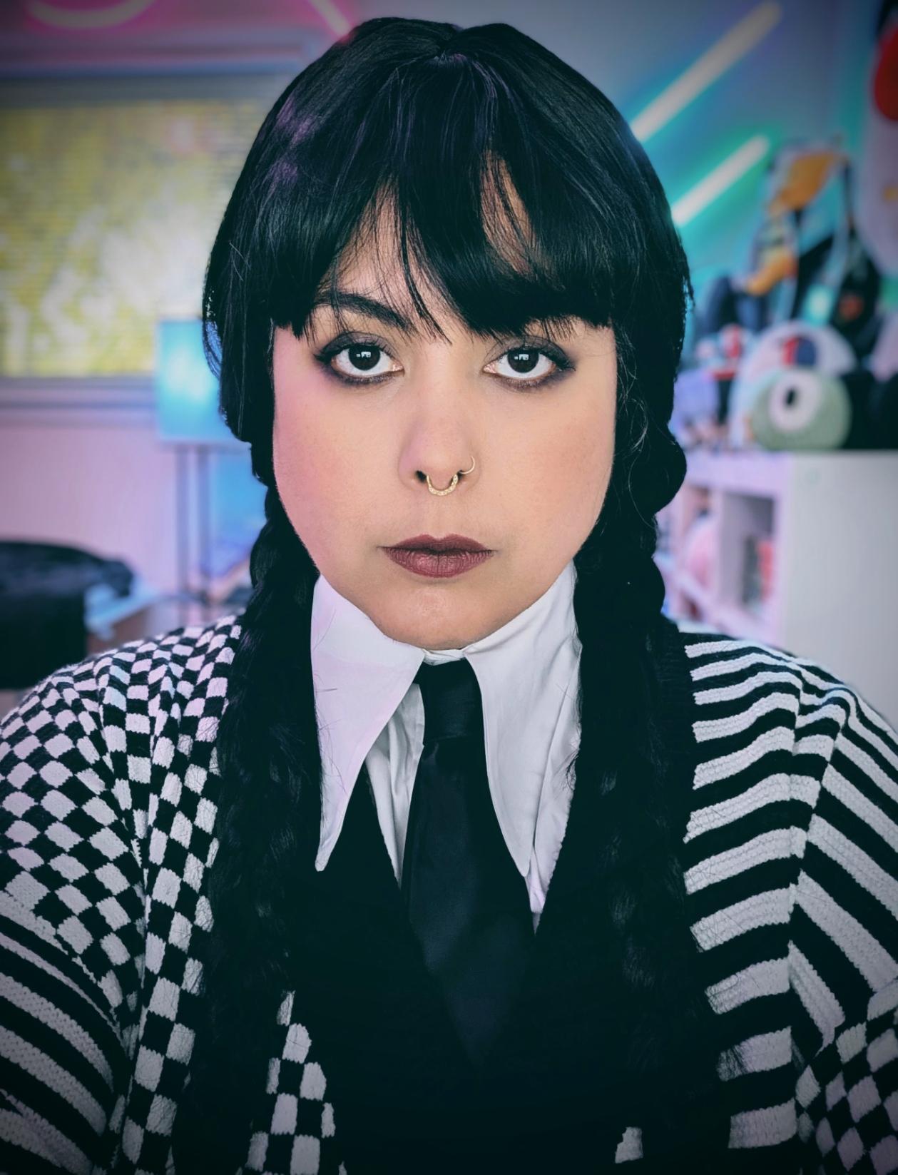 A portrait of a woman wearing a black wig in pigtails and a black and white sweater