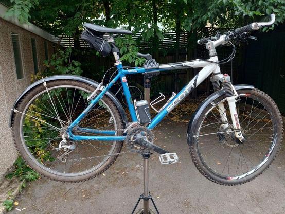 After: A 2001 Scott Yecora MTB with dropped bars & mudguards on a work stand. The frame is blue and white. The Marzocchi Z2 suspension fork is white.