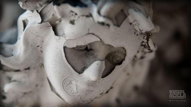 paint peeling from the face of a graveside angel statue.