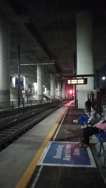 Creepy commuter rail station in a trench between two tunnels, under a freeway.