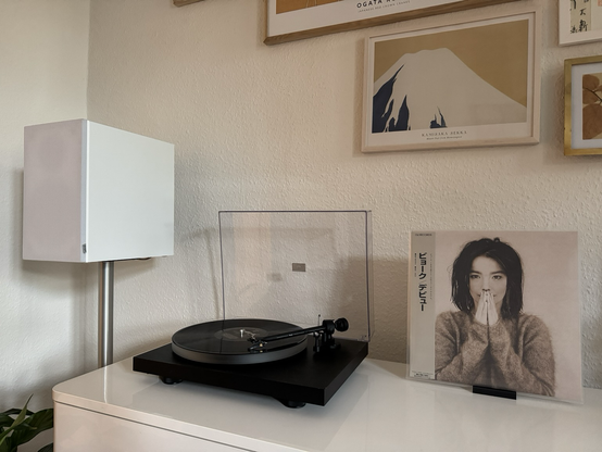 A record player playing a record. Next to it the cover of Björk‘s debut album, showing young Björk in Sepia colours. A white speaker on the left. A picture of Mount Fuji on the wall behind the setup.