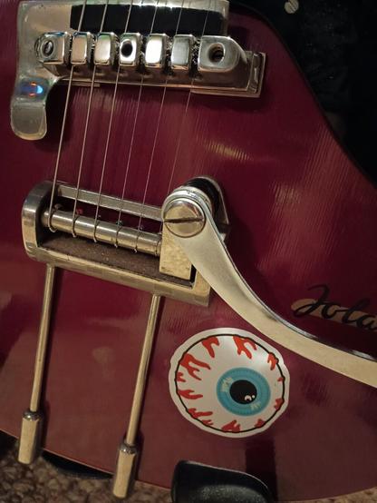 Foto einer roten Gitarre mit einem Augen-Aufkleber