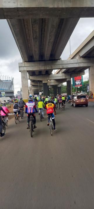 A group of cyclists on a highway in Nairobi under a bridge