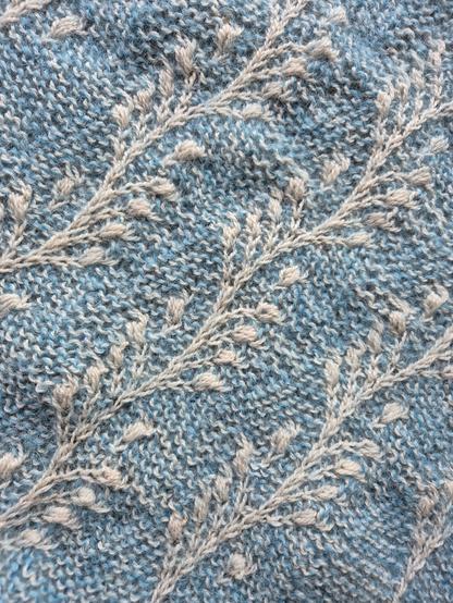 Noch kleinerer Ausschnitt des Hauptmusters. Auf hell blaugrünem Hintergrund verlaufen sandfarbene, fast weiße Linien wellenförmig, von denen immer wieder kurze Linien abgehen, die mit kleinen Knubbeln enden.