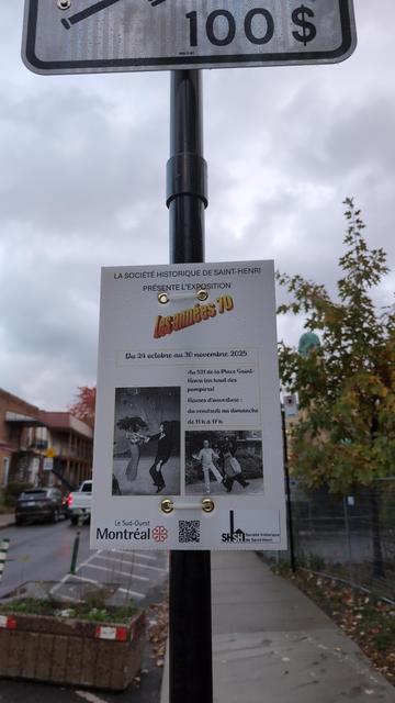 Poster says:

LA SOCIÉTÉ HISTORIQUE DE SAINT-HENRI PRÉSENTE L'EXPOSITION
Les années 70 [in the orange diagonal WordArt]
Du 24 octobre au 30 novembre 2025
Au 521 de la Place Saint-
Henri (en haut des pompiers)
Heures d'ouverture:
du vendredi au dimanche
de 11 h à 17 h

along with two black-and-white pictures of people dancing. The poster is attached to a pole with a "yield to pedestrian" sign on a sidewalk.