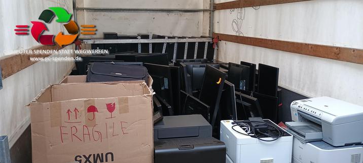 Blick in den Transporter wo Computer, Monitore, Kisten mit Kabel und Drucker stehen