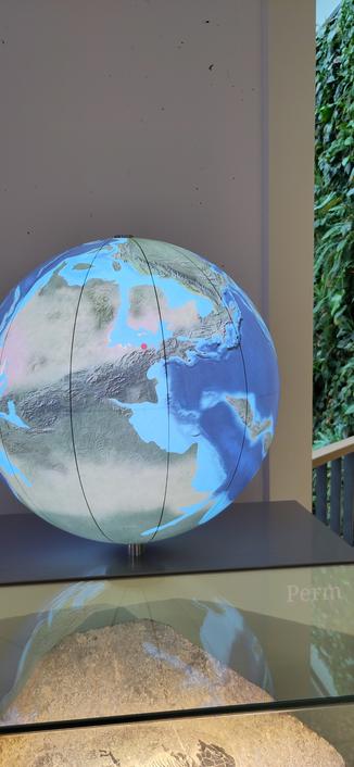 Globus zeigt die Welt im Perm mit viel Blau - roter Punkt an der Küste