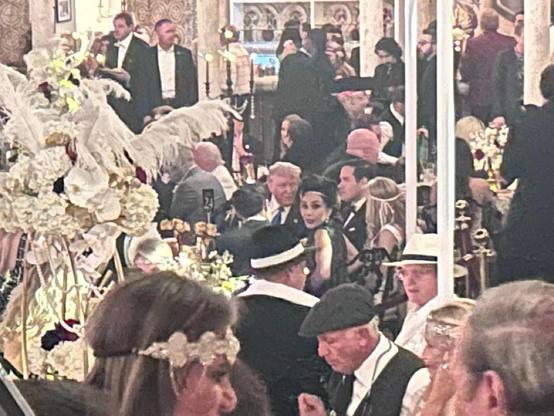 Trump at his Gatsby party in the middle of a crowd of celebrants dressed up like characters from the extravagant party in Fitzgerald's roaring twenties.