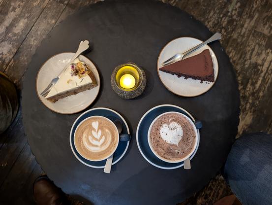 Ein runder Tisch mit Kerze, zwei Stück Kuchen und zwei Tassen Kaffee