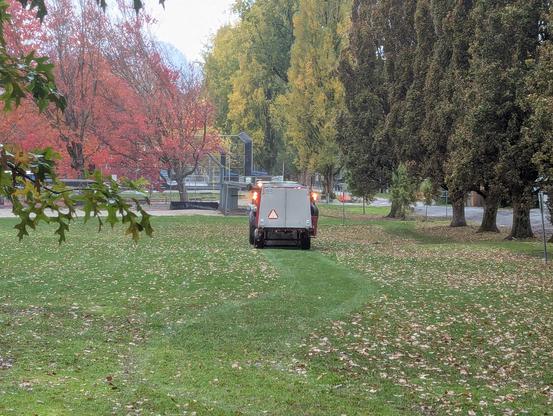 the leaf removal trailer leaves a leafless trail on the grass behind it