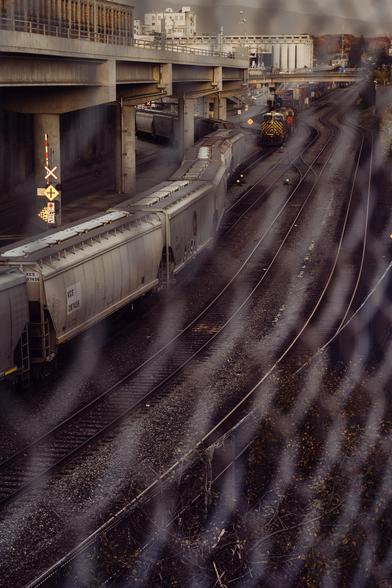 Rail lines arc into the distance through a chain-link fence.