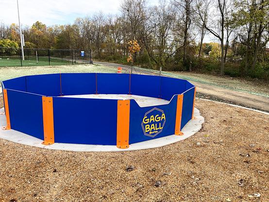 A small gaga pit made out of thin (approximately 2 cm thick) composite blue and orange materials on a concrete slab.