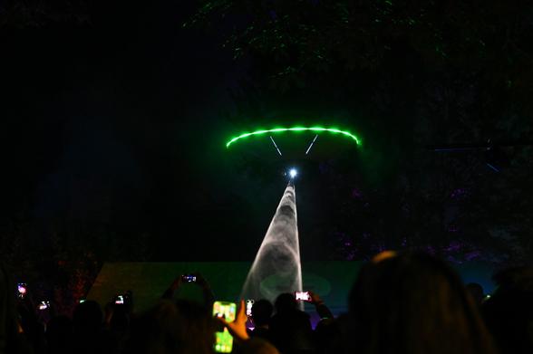 a flying spaceship hovers above crowd of iPhones