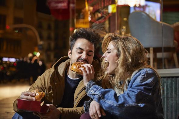 Un hombre y una mujer, están sentados comiendo una hamburguesa. (Getty Images)