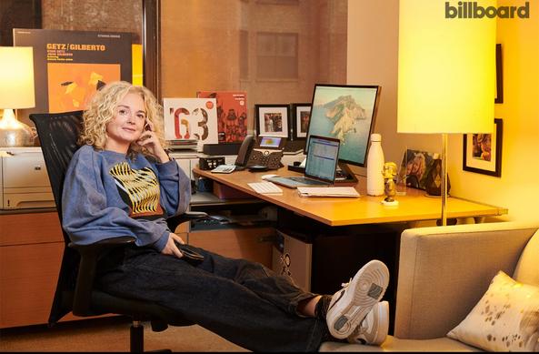 Dahlia sitzt an ihrem Schreibtisch. im Hintergrund stehen prominente Verve-Platten. Das Licht des Fotos ist honiggelb.