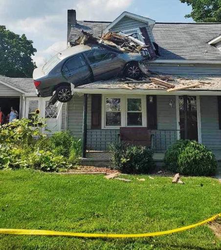 Car crashed into the first story of a house with a green lawn.