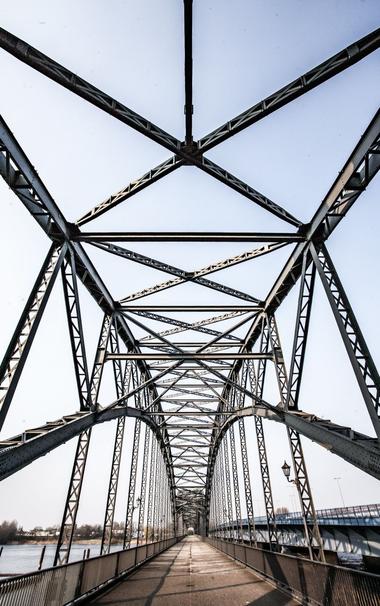 Blick aus Spazierperspektive von unten auf die Stahlkonstruktion der Brücke. Der Himmel ist klar.