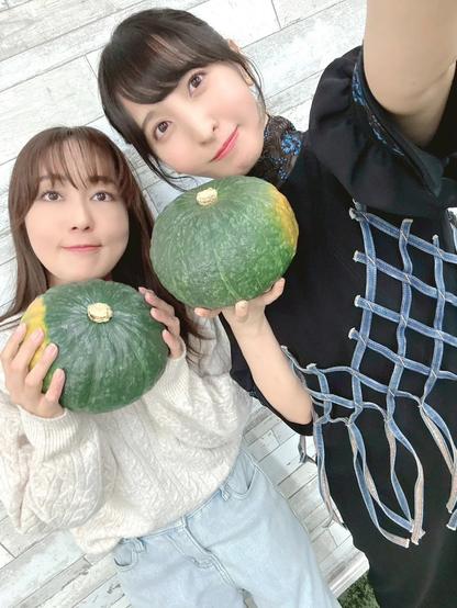 A selfie of two women smiling holding pumpkins.
