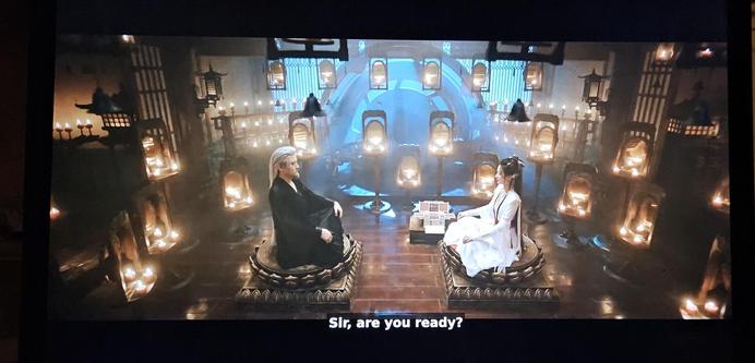 The master and the doctor sitting crosslegged facing each other. The room is lit by hundreds of red candles.